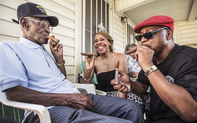 Richard Overton, left,  smokes a cigar with a few neighborhood friends Donna Shorts, center and Martin Wilford Sunday, May 3, 2015, in Austin, Texas.. Overton, is considered to be the oldest living World War II veteran in the United States, celebrated his 109th birthday on a front porch in East Austin with friends and family. Wilford, right, says that he has known Overton for 37 years and he looks at Mr. Overton as if he was his biological father.  (Ricardo B. Brazziell/Austin American-Statesman via AP)